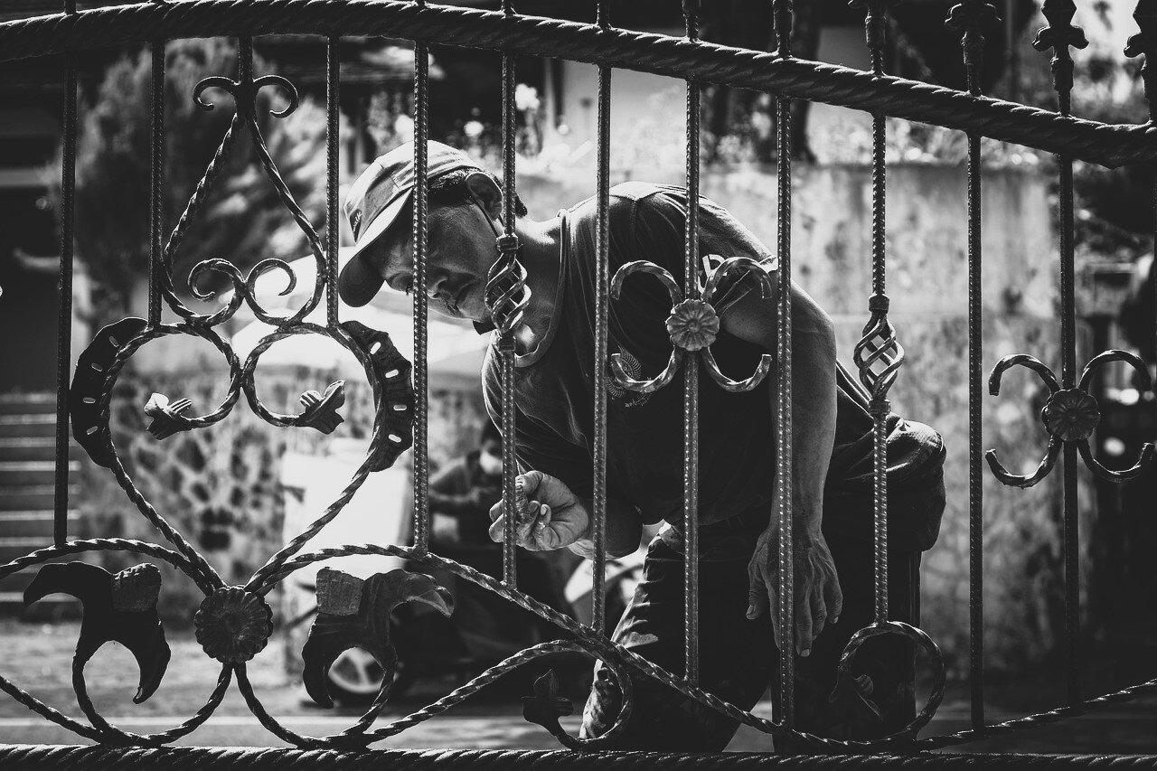 An older man painting a gate